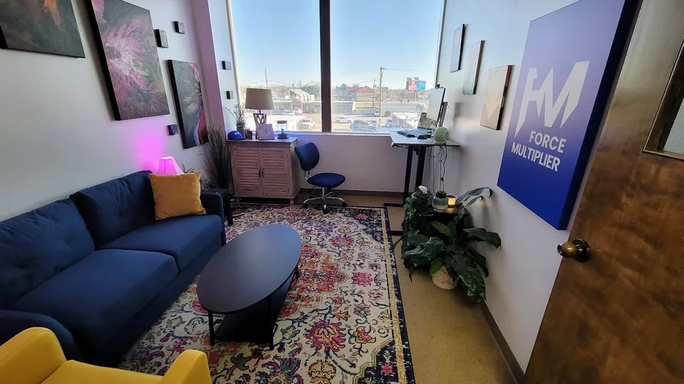 Force Multiplier workspace with a blue sofa, yellow chair, artwork and the Force Multiplier wall sign